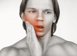 Young Male Holding Cheek in Pain